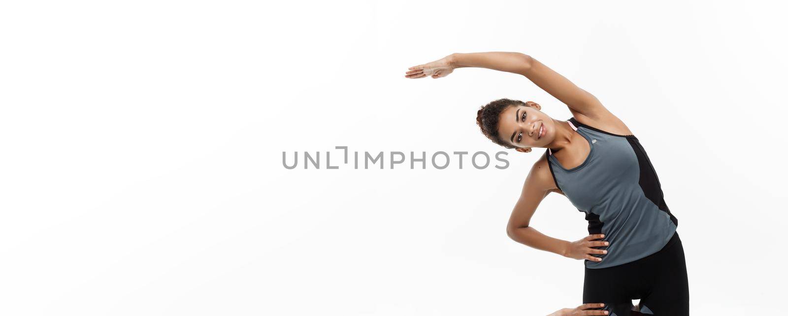 Sport, training, lifestyle and Fitness concept - portrait of beautiful happy African American woman stretching hands. Isolated on white studio background