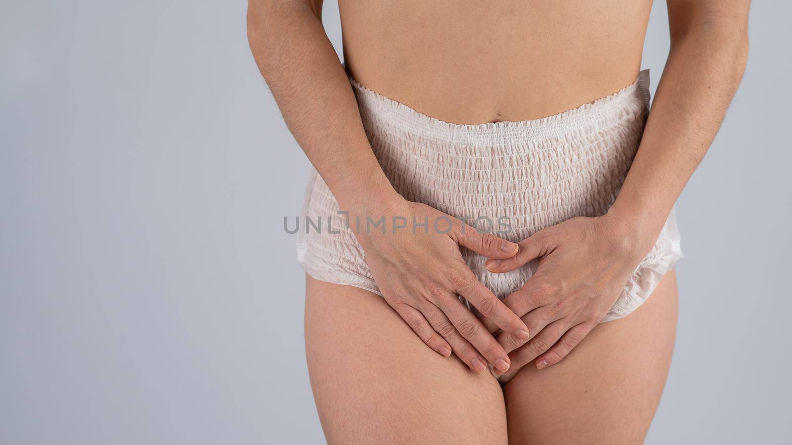 A woman in adult diapers holds her hands on her stomach. Urinary incontinence problem. by mrwed54