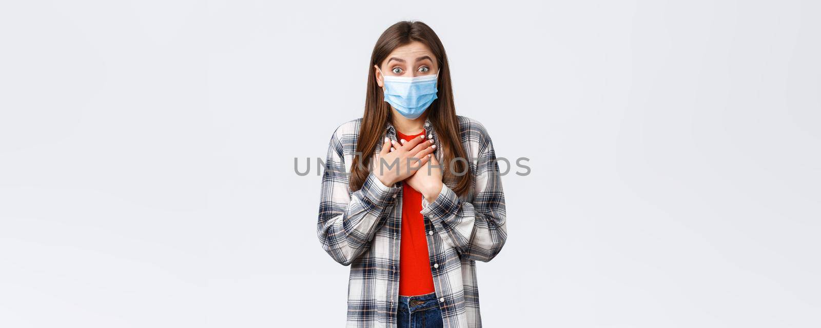 Coronavirus outbreak, leisure on quarantine, social distancing and emotions concept. Touched happy cute girl in medical mask, press hands to chest looking at something beautiful, hear good news.