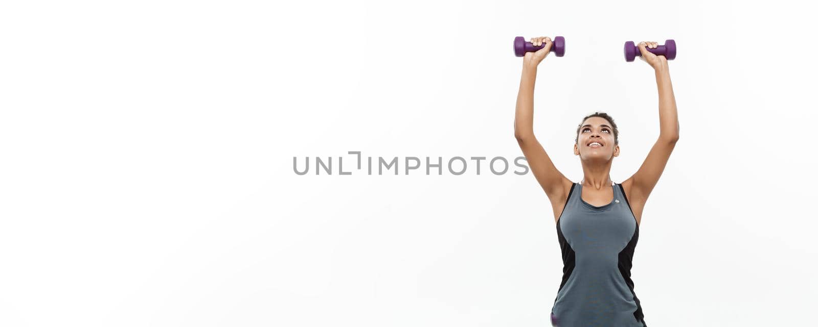 Healthy and Fitness concept - Beautiful American African lady in fitness clothes workout with dumbbell. Isolated on white background. by Benzoix