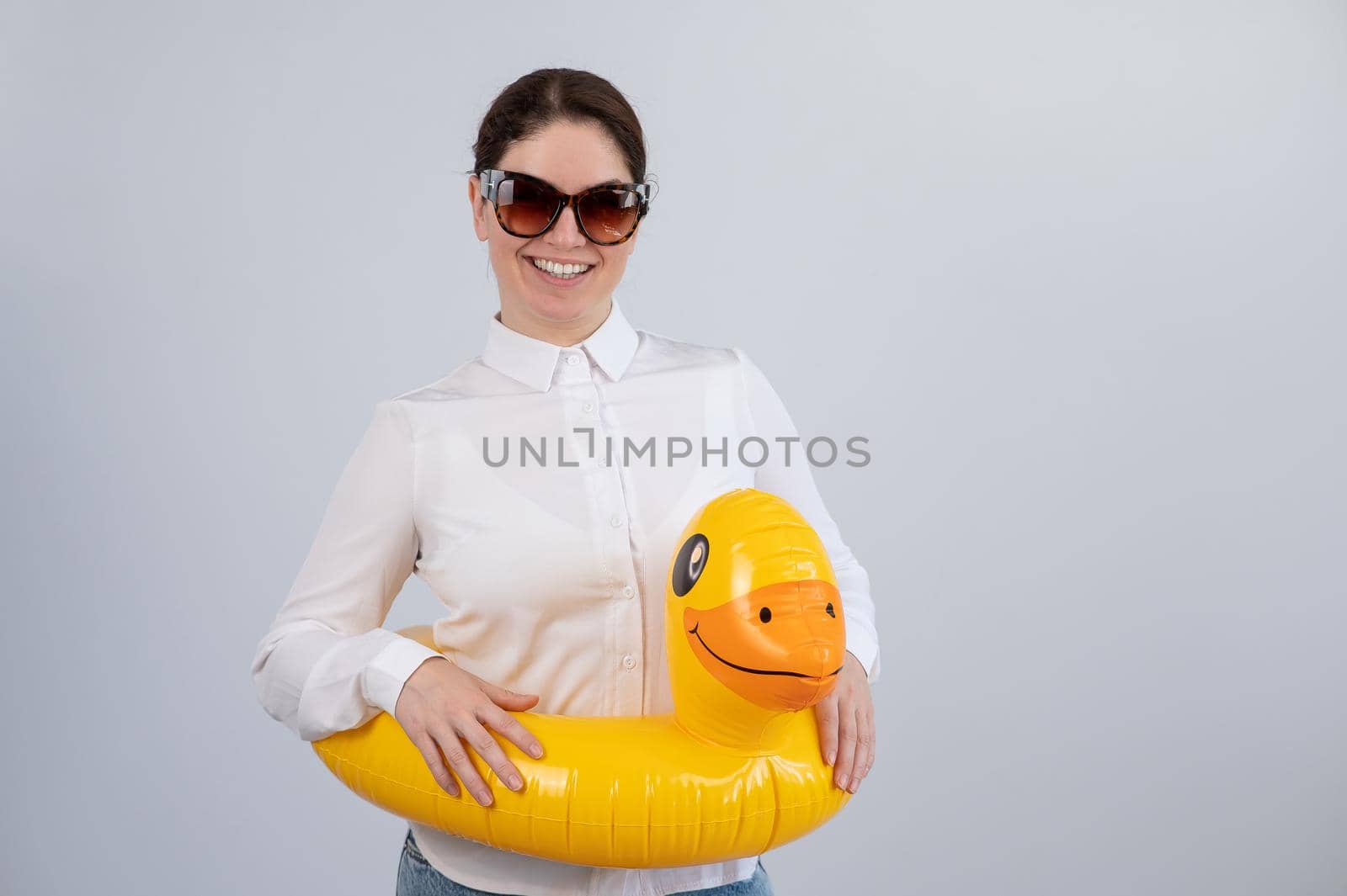 Caucasian woman in a white shirt dreaming of a vacation and wearing sunglasses and an inflatable duck