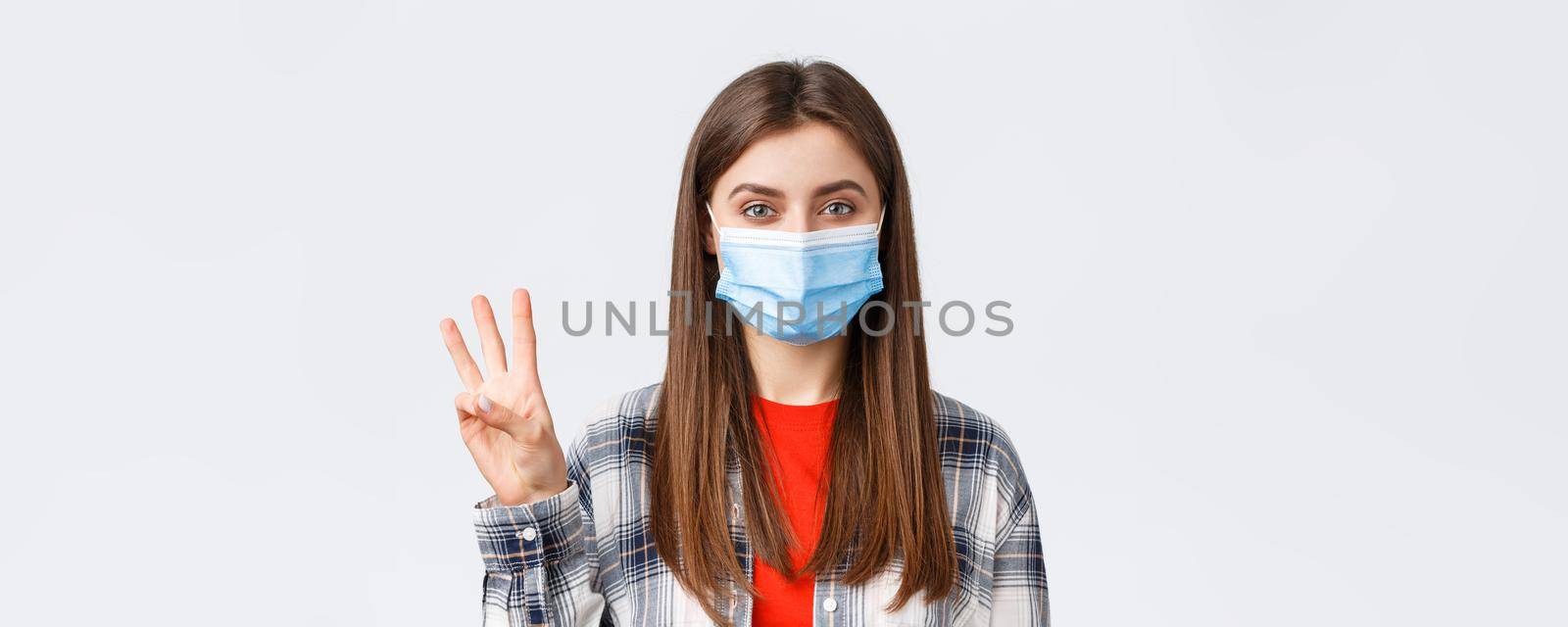 Coronavirus outbreak, leisure on quarantine, social distancing and emotions concept. Close-up of cheerful attractive woman in medical mask show number three, third, white background.
