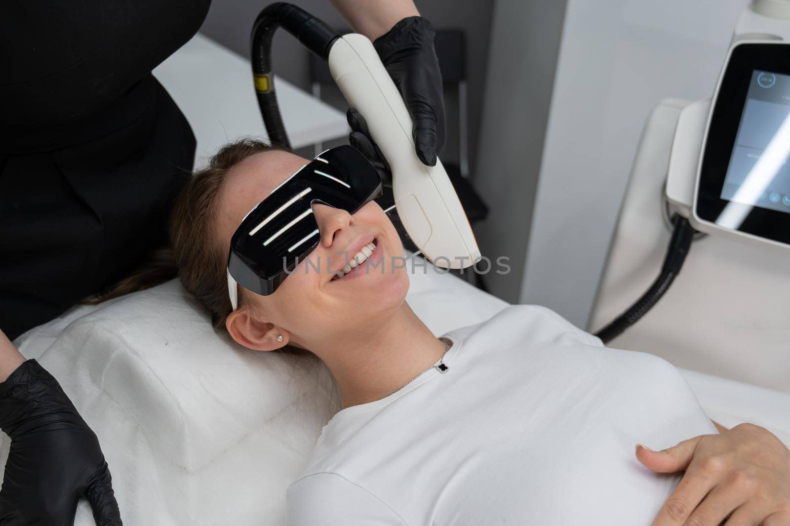Young caucasian woman in goggles on photorejuvenation procedure. Portrait of a girl in a beautician's clinic