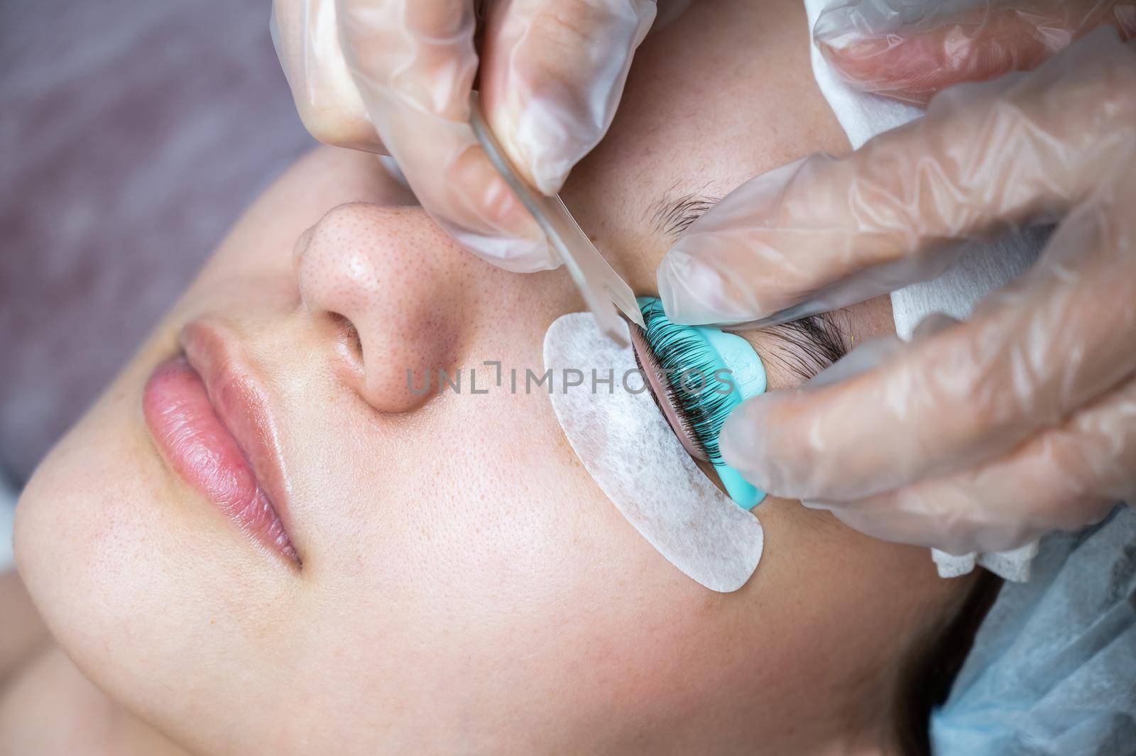 The master combs the eyelashes of a woman with a fish applicator