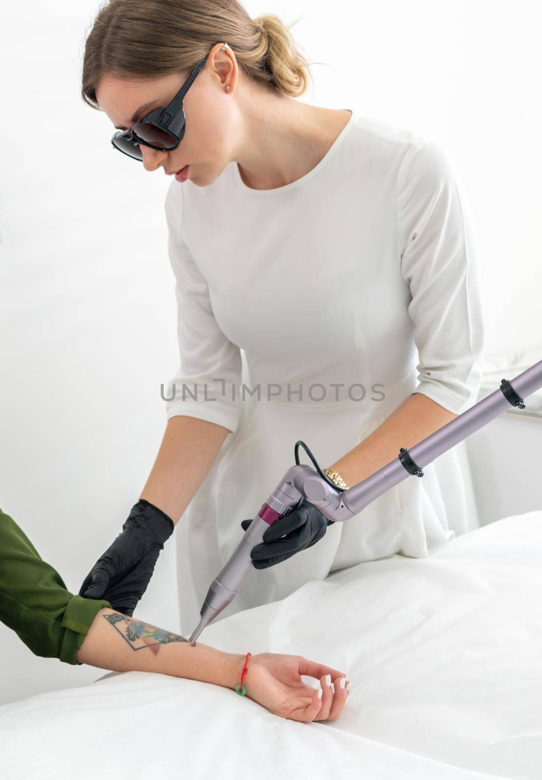 Cosmetologist removing tattoo with laser device female hand. Concept of erasing tattoos as expensive procedure in cosmetology clinic