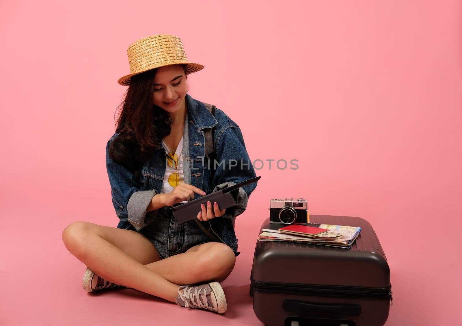 young asian woman backpacker traveler holding tablet. journey trip travel. studio shot