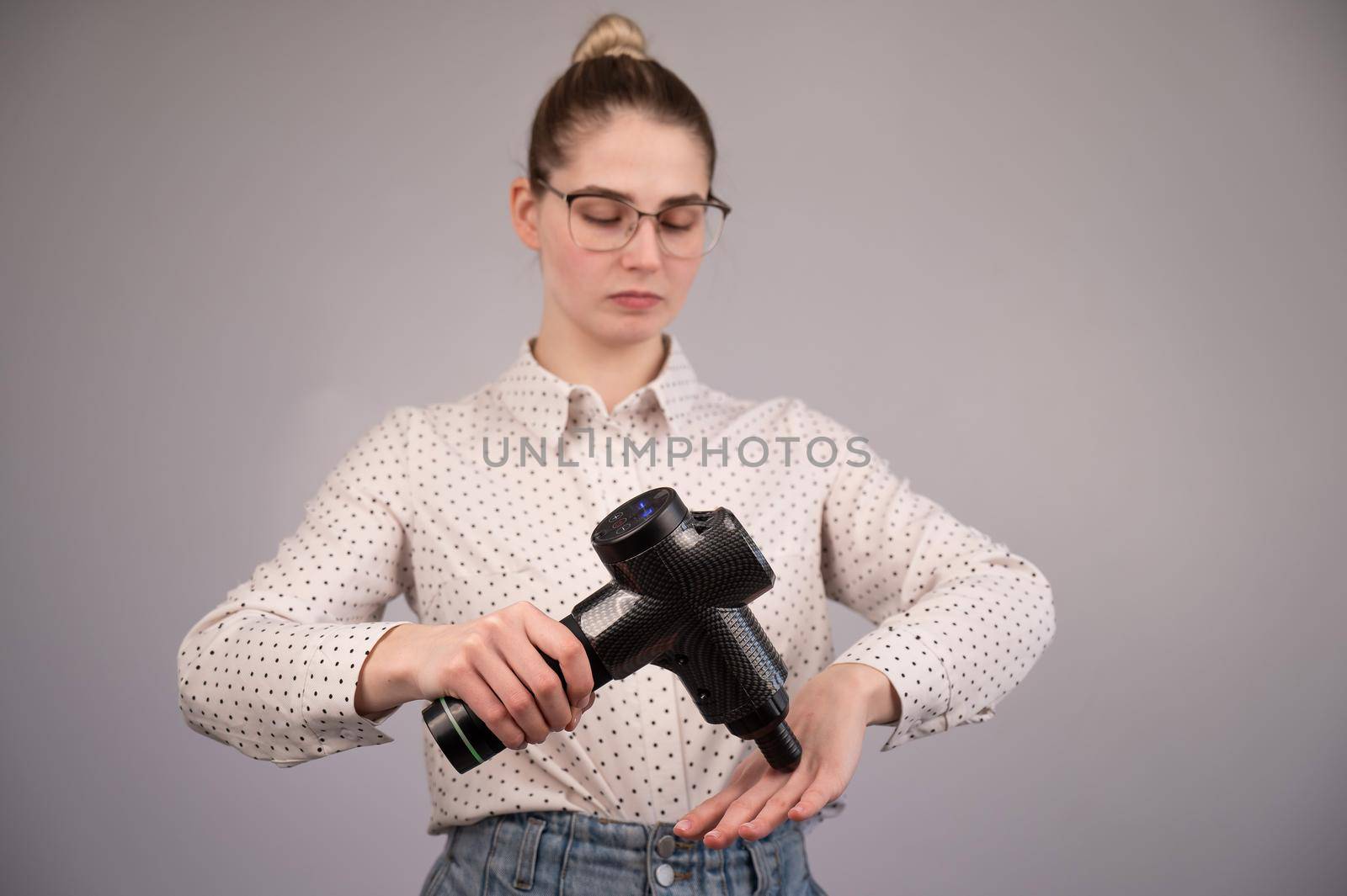 Caucasian business woman massaging her wrist with a percussion massager