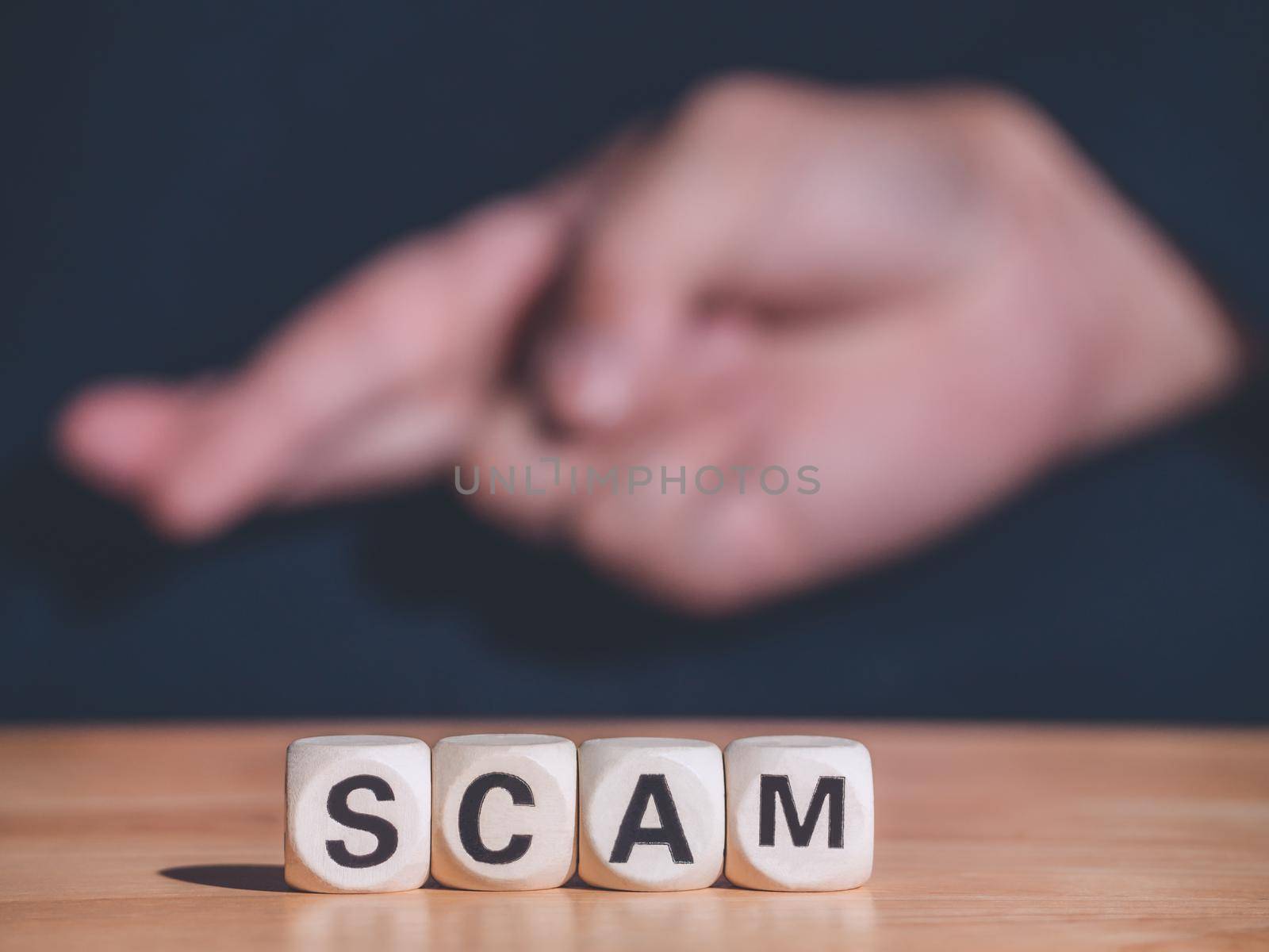 SCAM word made with building wooden blocks on table front of hand of sign language. Business concept and copy space. by Chakreeyarut