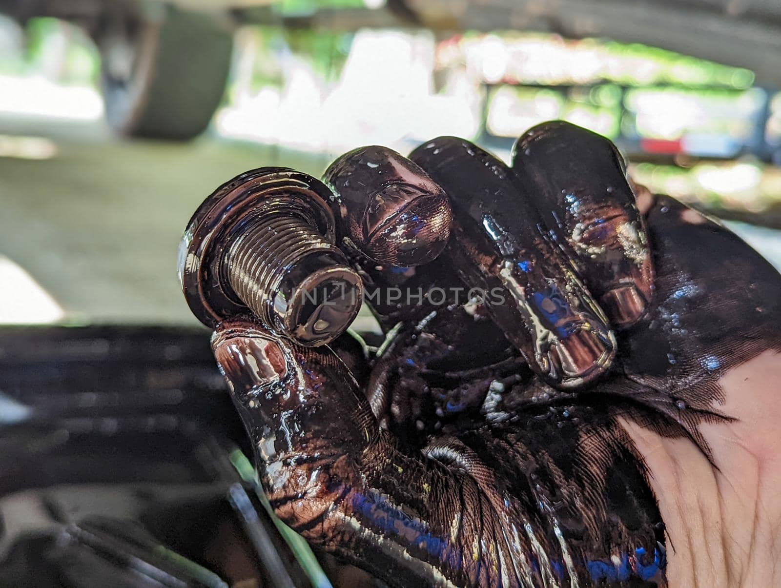 view of auto mechanic with mud on hands changing car oil by digidreamgrafix