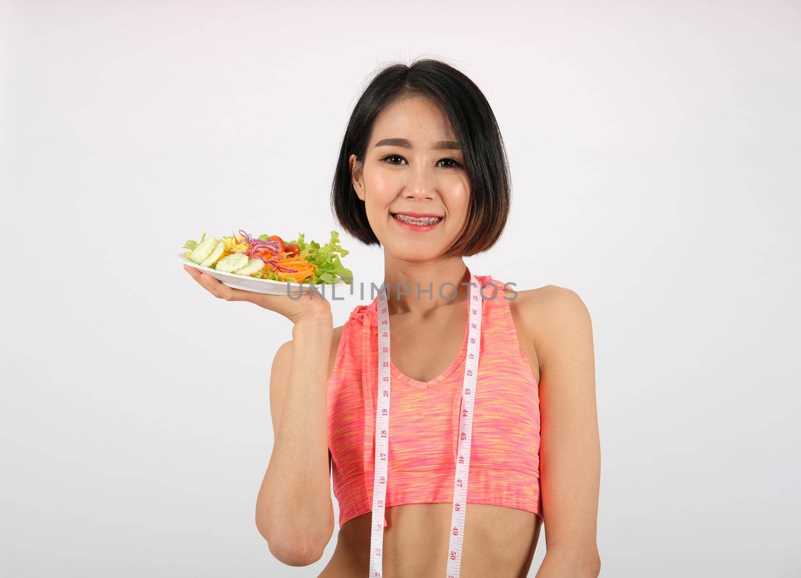 sporty fitness woman in sportswear with vegetable salad bowl on white background. healthy sport lifestyle