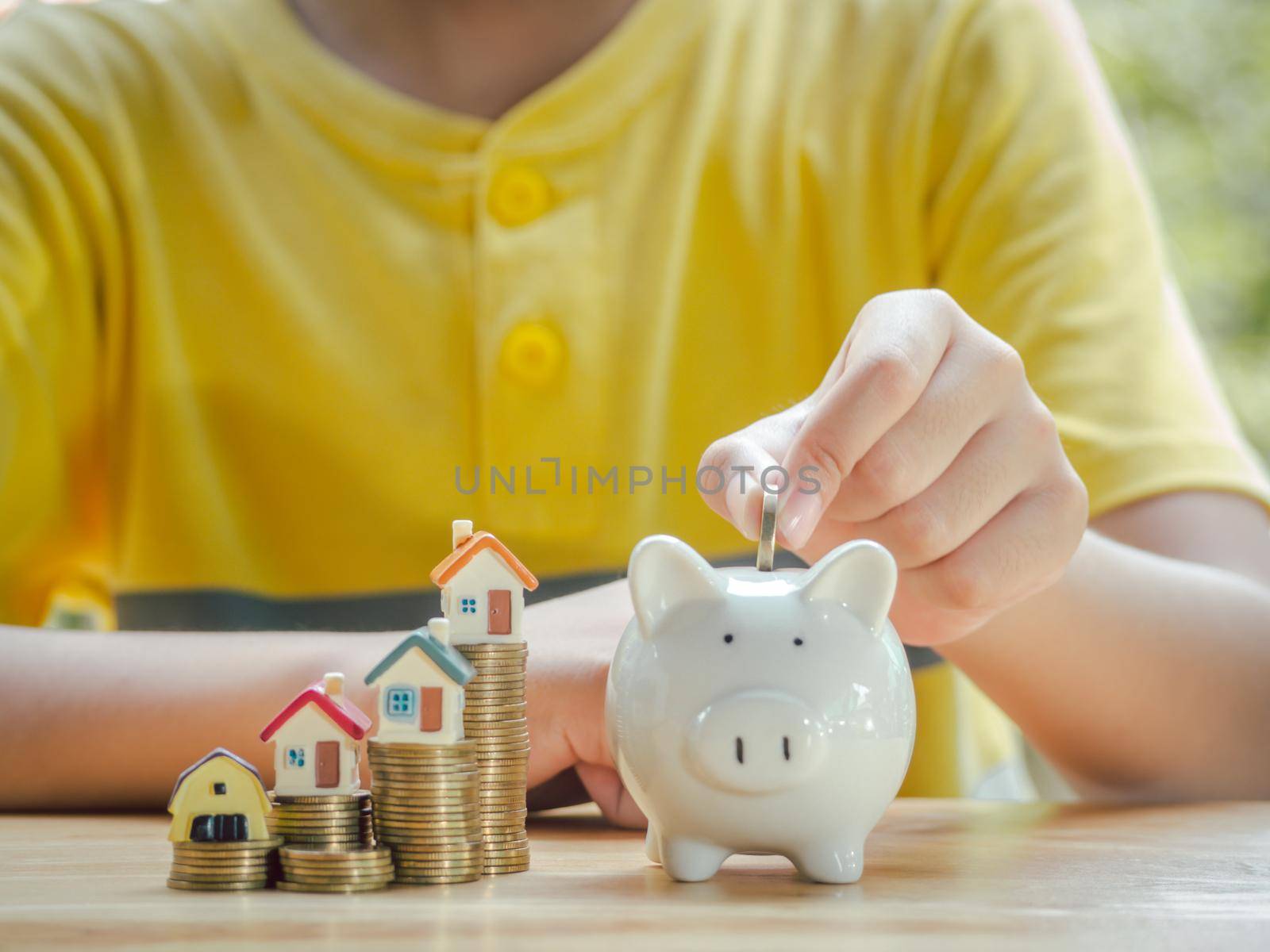 Asian boy holding coins drop a container saving money to save money invest for future and buy home.Concept loan, property ladder, financial, real estate investment and bonus. by Chakreeyarut