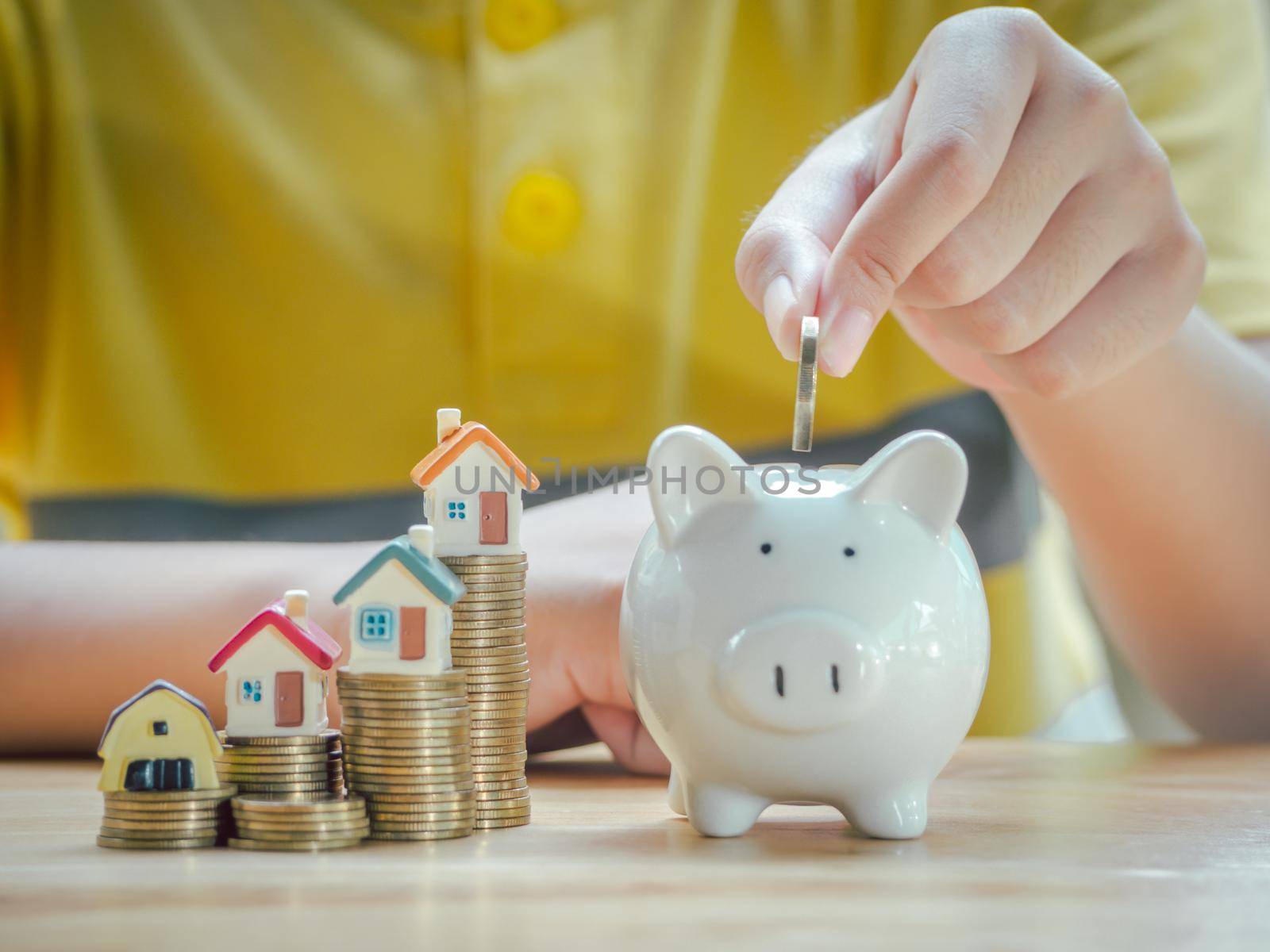 Asian boy holding coins drop a container saving money to save money invest for future and buy home.Concept loan, property ladder, financial, real estate investment and bonus.