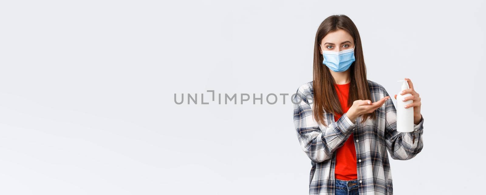 Coronavirus outbreak, leisure on quarantine, social distancing and emotions concept. Young woman taking care of health, preventing virus measures, apply soap or hand sanitizer, wear medical mask.