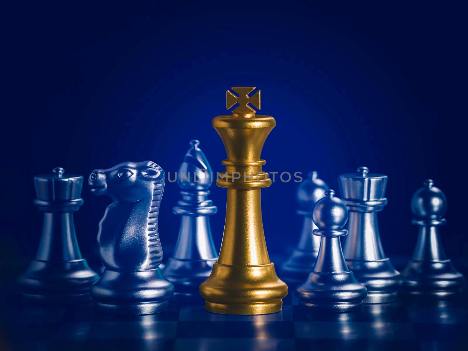 Golden king chess is surrounded by falling around silver chess pieces  to fighting with teamwork to victory, business strategy concept and leader and teamwork concept for success. by Chakreeyarut