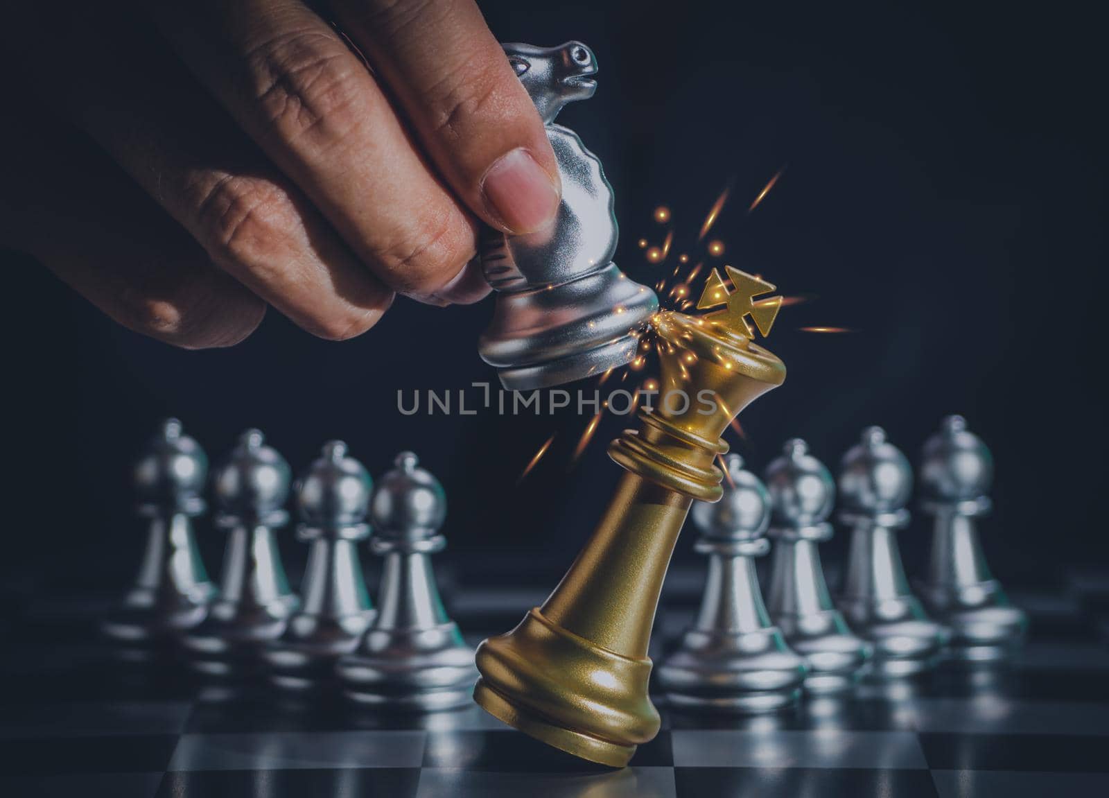 Hand businessman moving the silver knight chess fighting gold king with fire sparks chess on chess board to successfully in the competition. Management or leadership strategy and teamwork concept. by Chakreeyarut