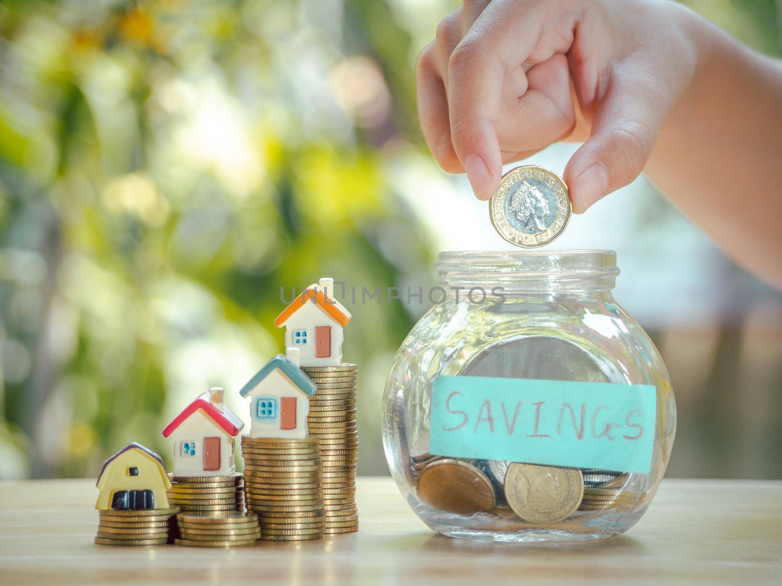 Asian boy holding coins drop a container saving money near home on gold coins stack to save money invest for future and buy home.Concept loan,property ladder,financial, real estate investment, bonus. by Chakreeyarut
