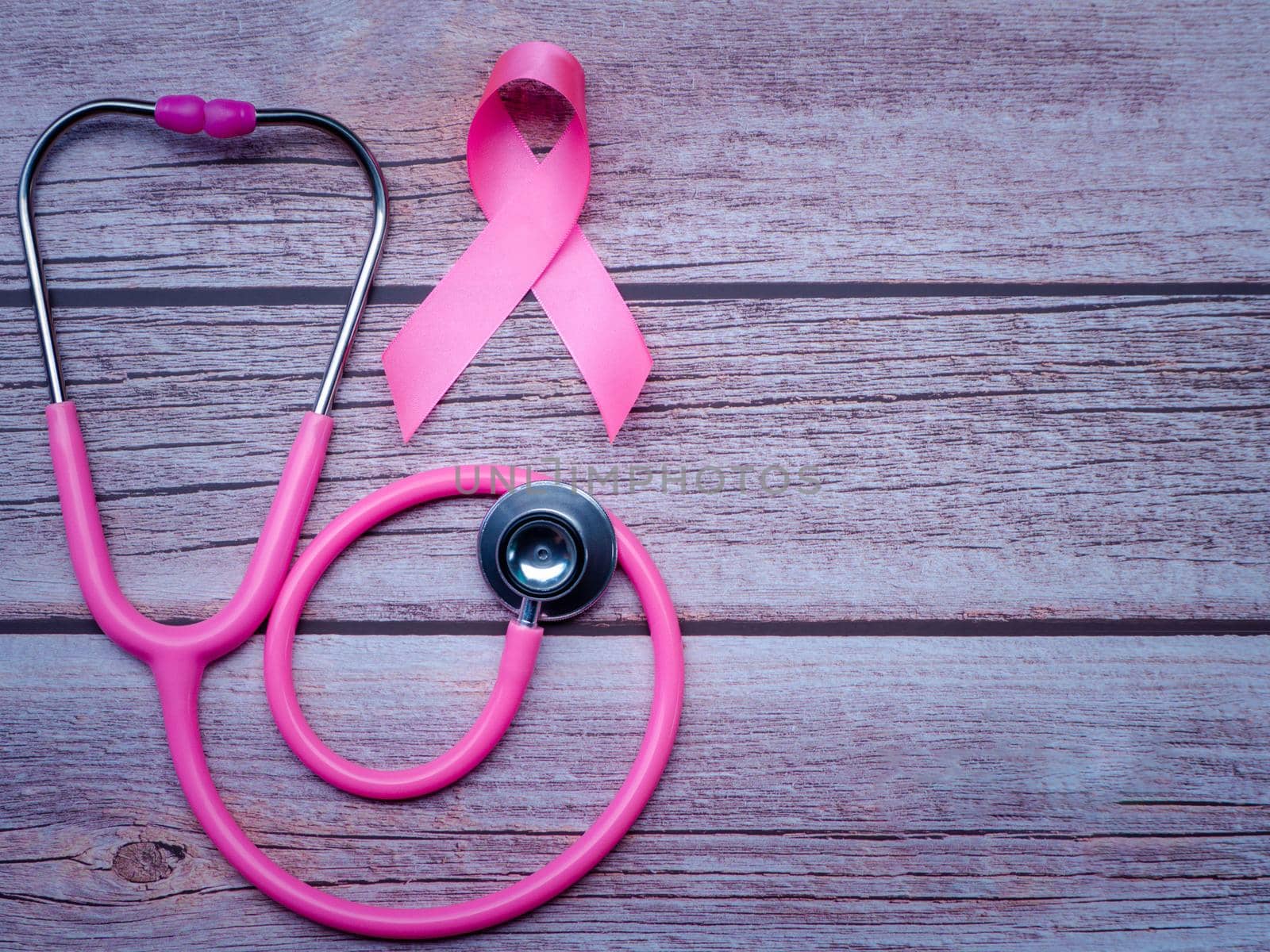 Pink ribbon and stethoscope on wooden table vintage style. Symbol of breast cancer, health care concept by Chakreeyarut