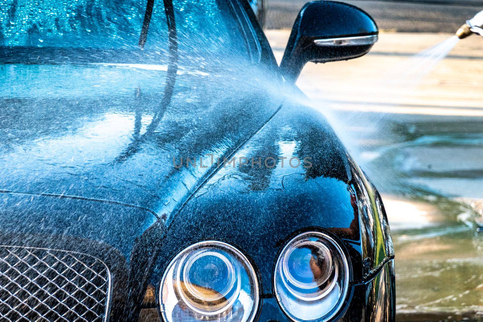 auto detailer washing luxury high end car by digidreamgrafix