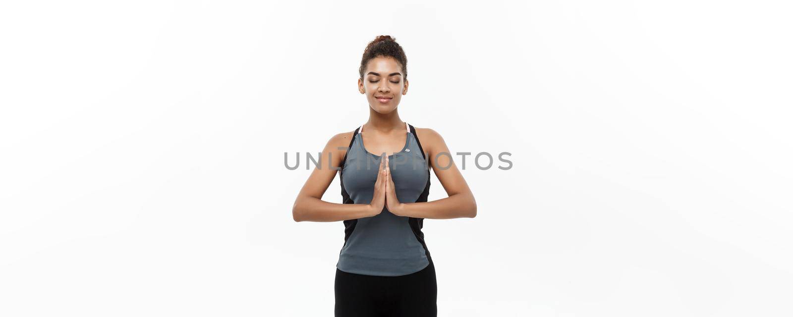 Healthy and Fitness concept - Beautiful American African lady in fitness clothing doing yoga and meditation. Isolated on white background. by Benzoix