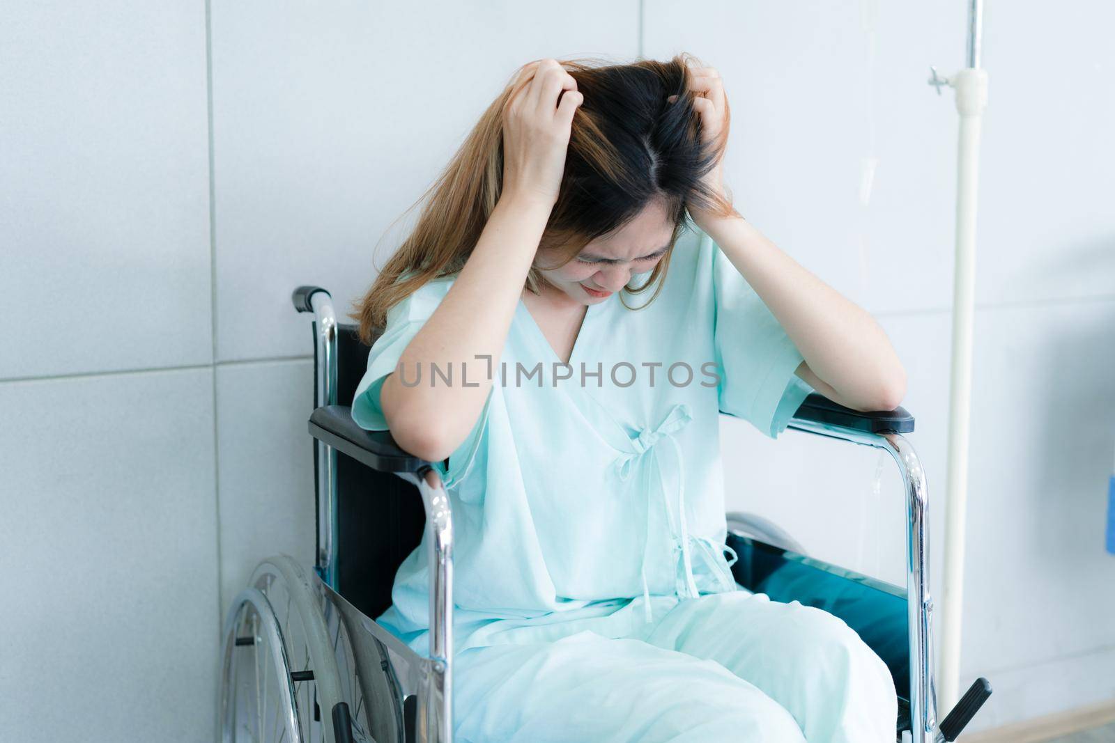 A woman sit on a wheelchair at hospital.  Sick and stressed