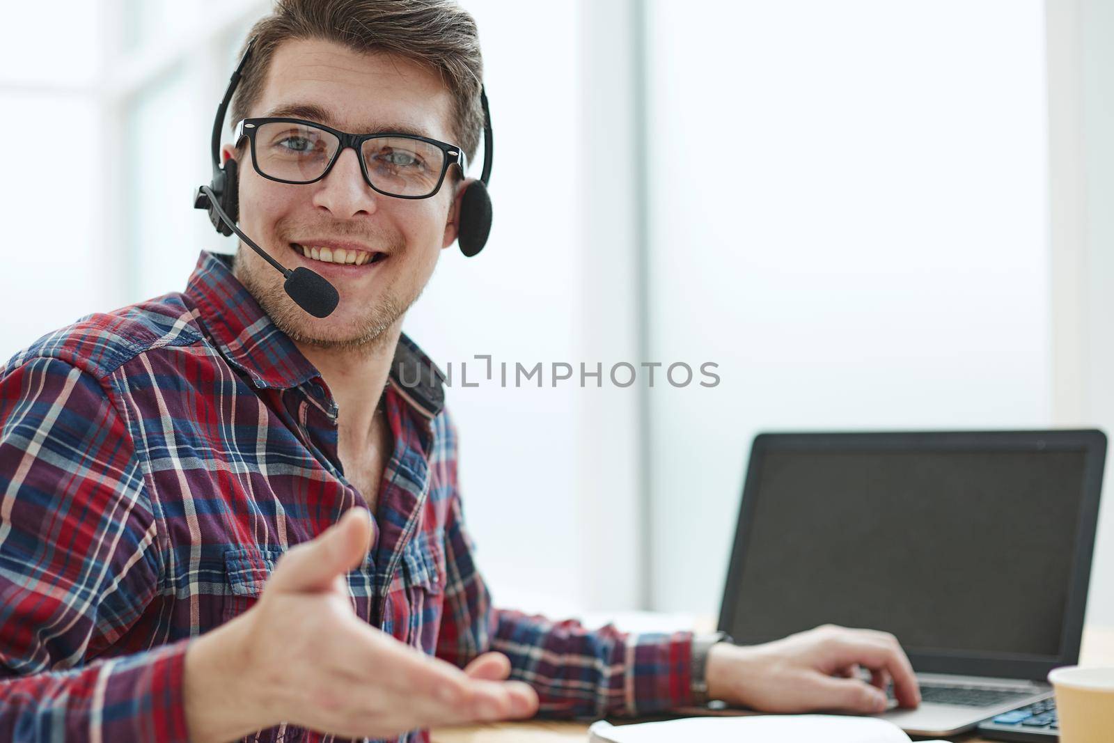 Portrait of handsome male customer service in headphones. Call center staff speaking with head set in modern office by Prosto