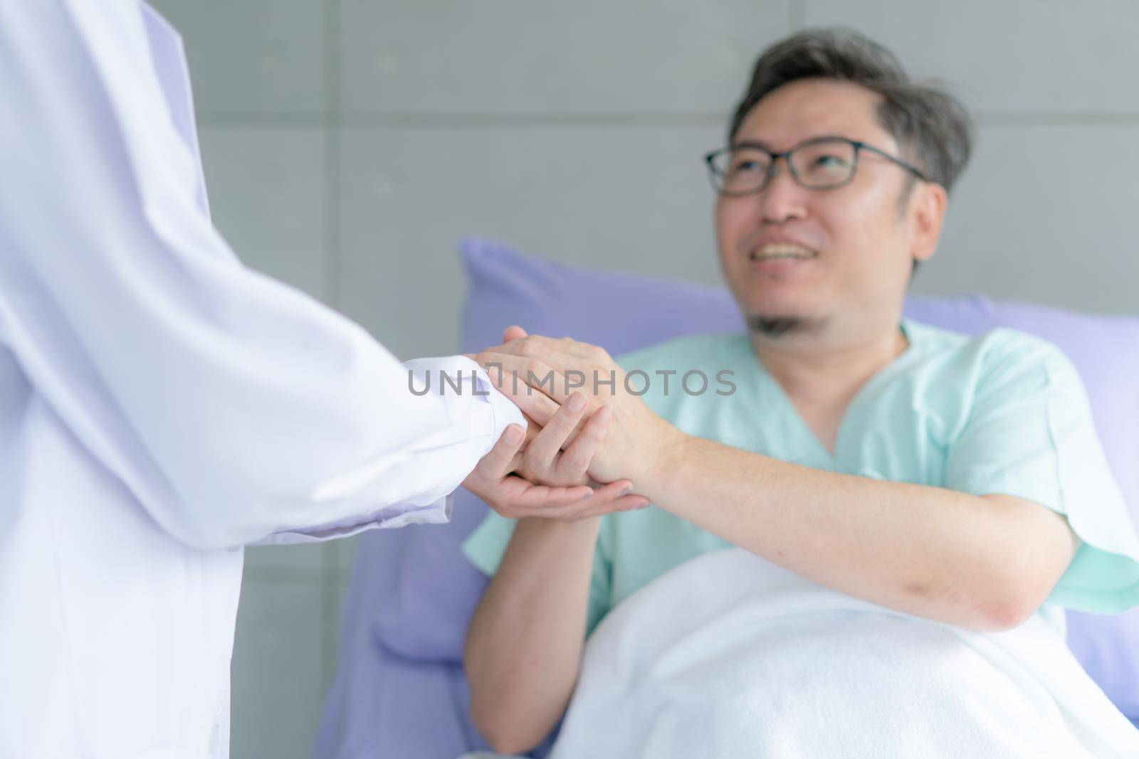 Smiling thankful sick man holding doctor hand appreciation for help support care.  Thank you doctor or nurse.