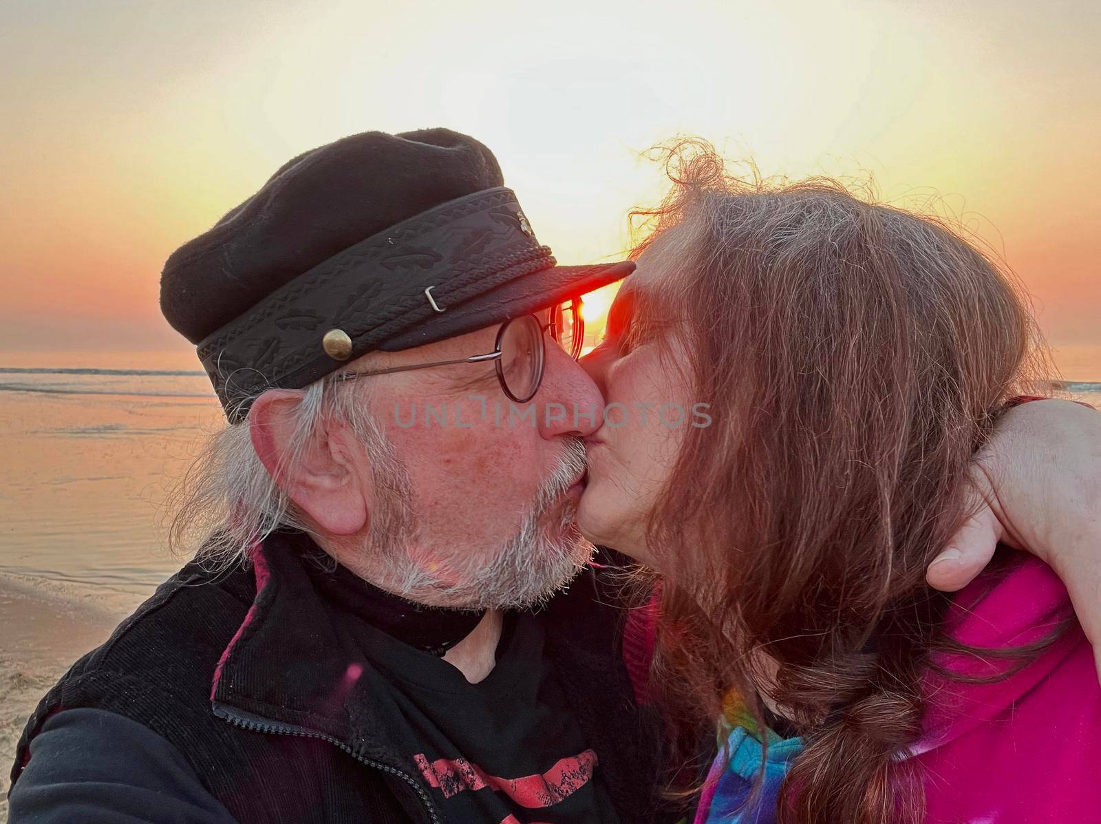 Kissing elderly couple on the beach at sunset. Location: Noordwijk aan Zee, Netherlands