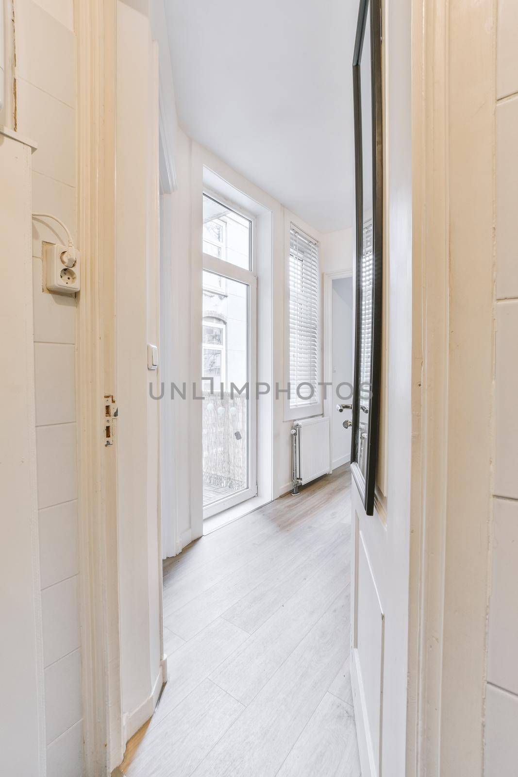 Room with door to balcony and narrow long corridor in perspective in modern house with ceiling beams