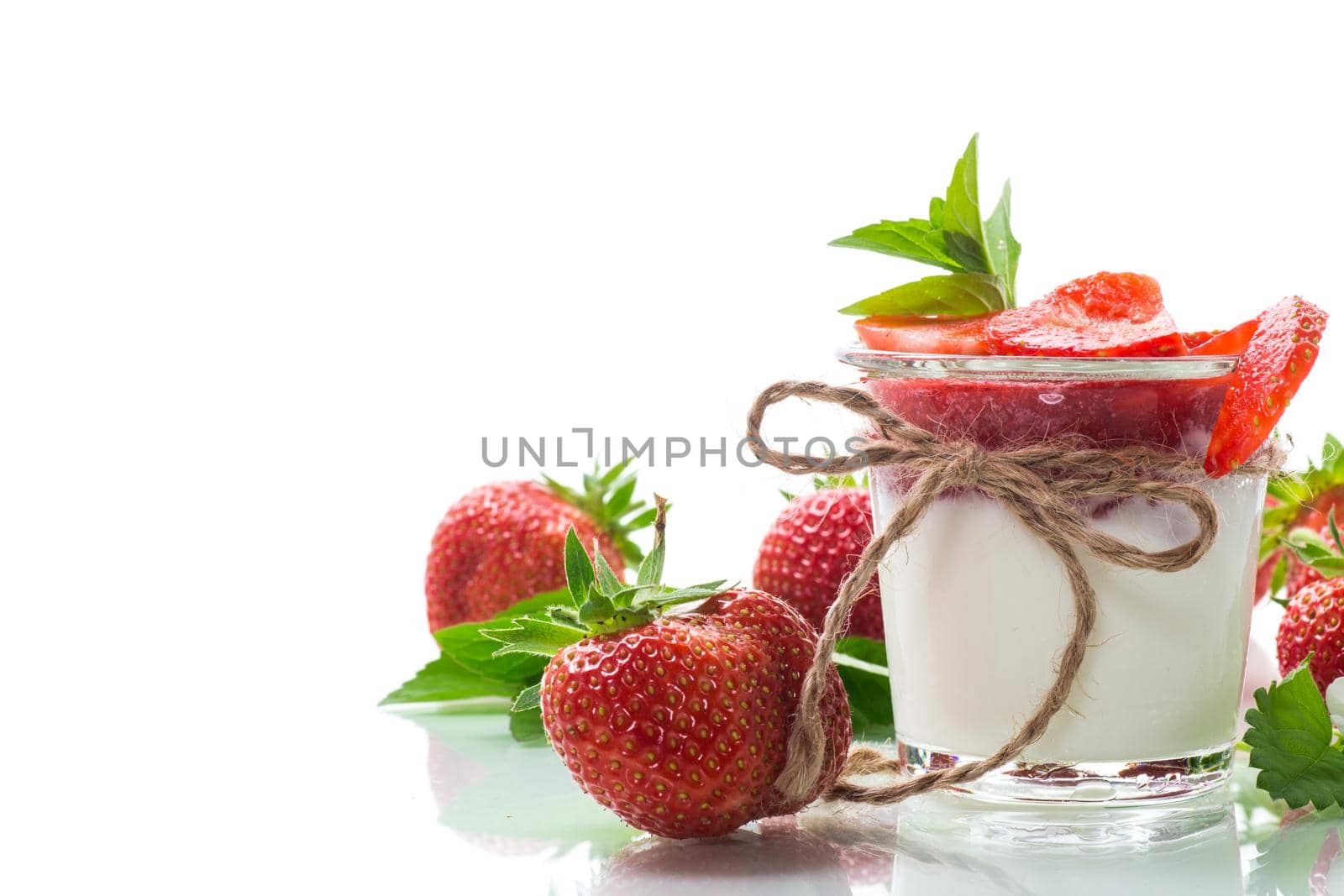 sweet homemade yogurt with strawberry jam and fresh strawberries in a glass, isolated on white background.