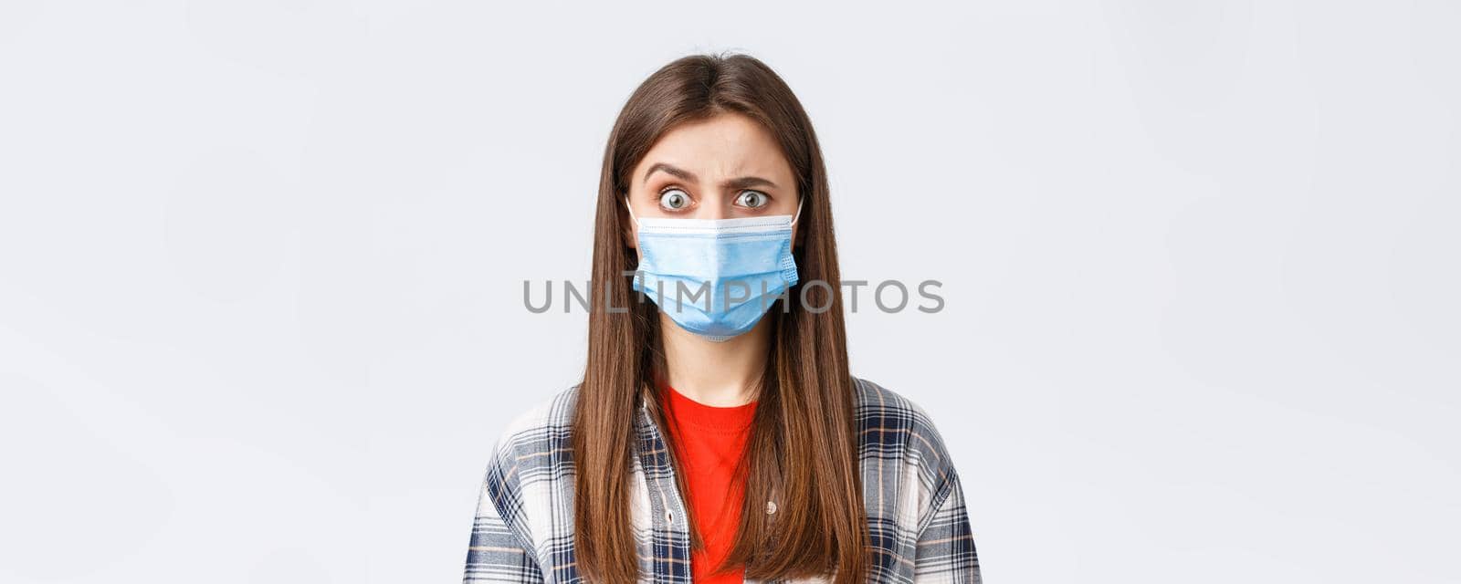 Coronavirus outbreak, leisure on quarantine, social distancing and emotions concept. Confused and startled girl in medical mask seeing something strange, raise eyebrow skeptical.
