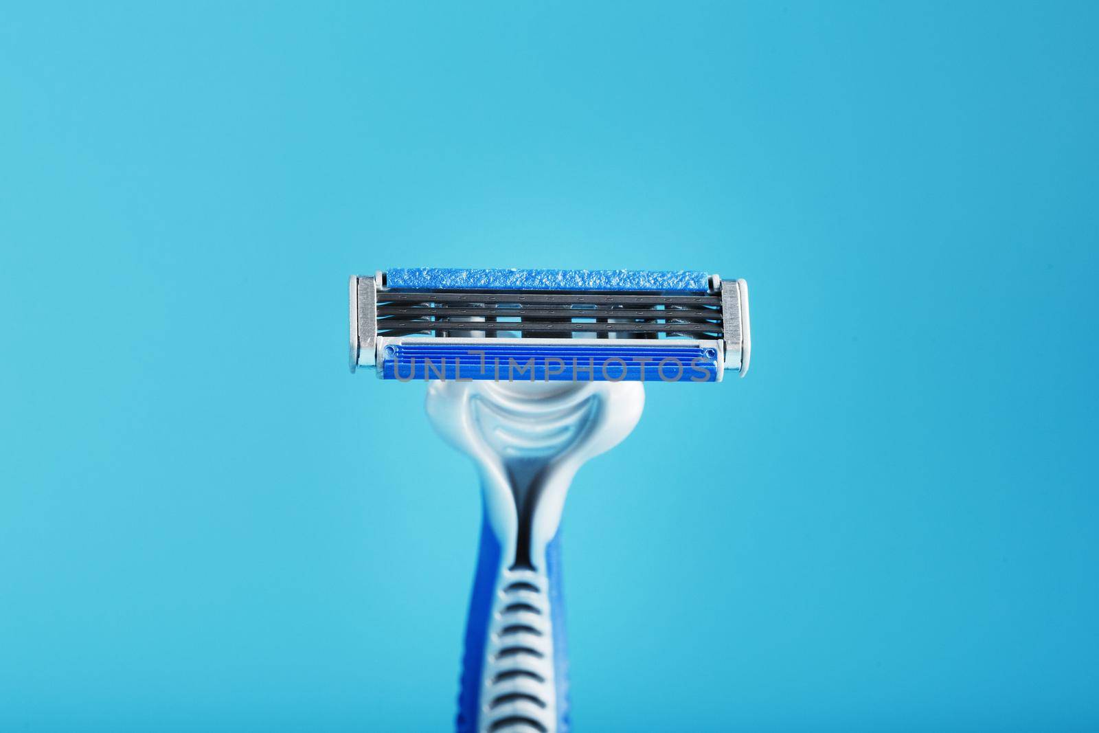 Shaving machine with three blades on a blue background close-up free space by AlexGrec