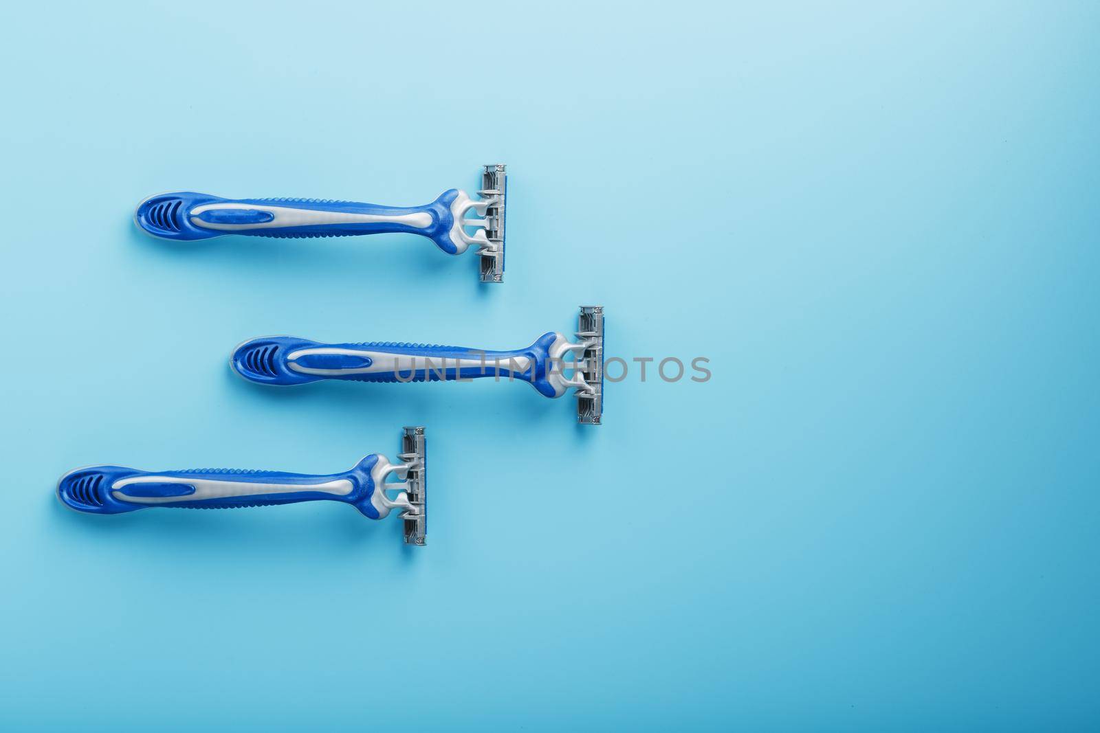 Blue shaving machine with sharp blades on the background of ice cubes close-up. The concept of cleanliness and frosty freshness