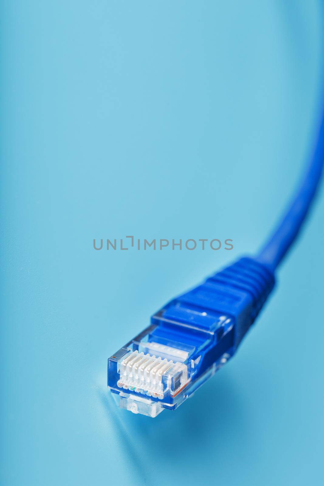 A coil of an Internet network cable for data transmission on a blue background. Patch cord for LAN cable.