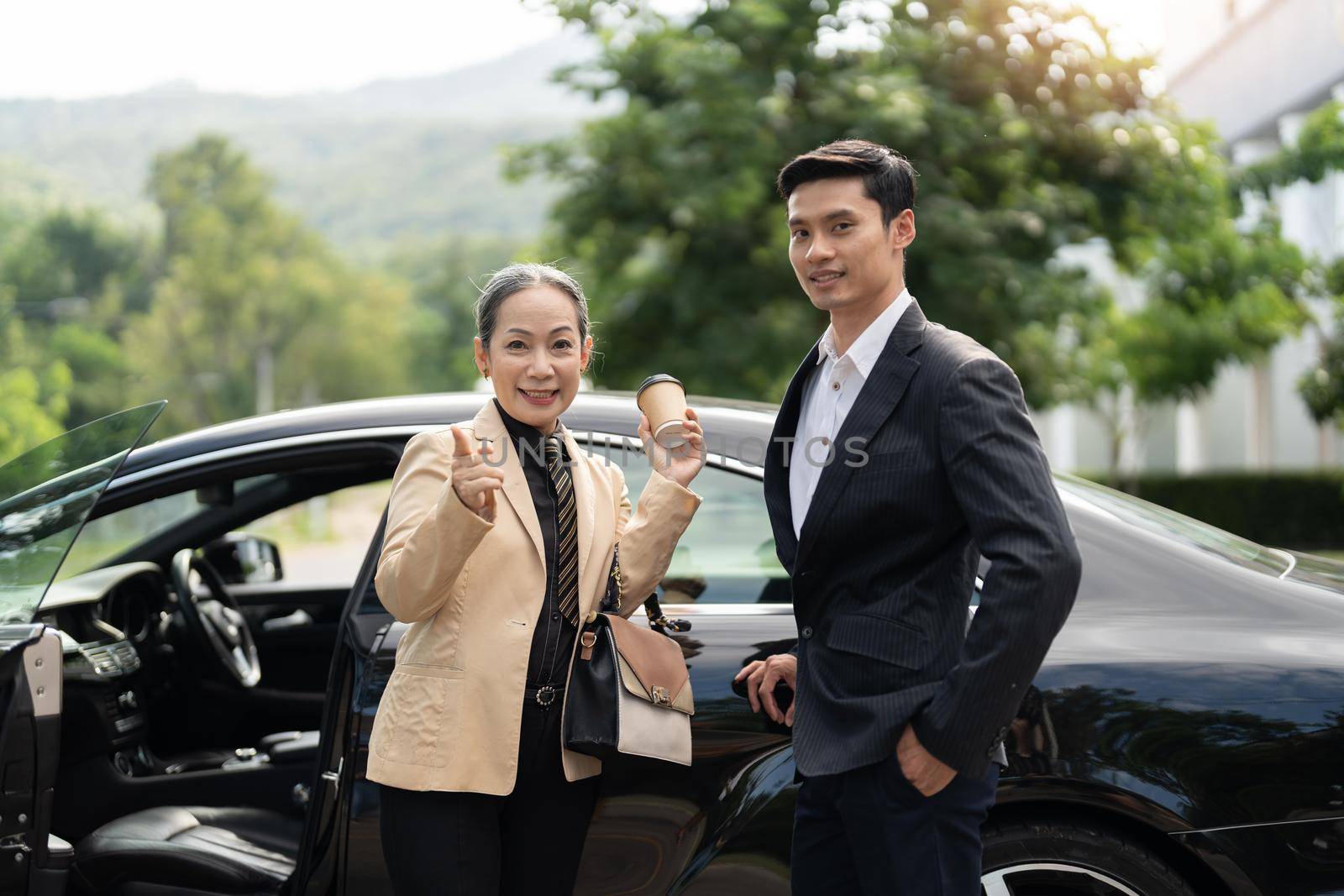 Happy senior old asian businesswoman and young asian male colleague at car park by nateemee