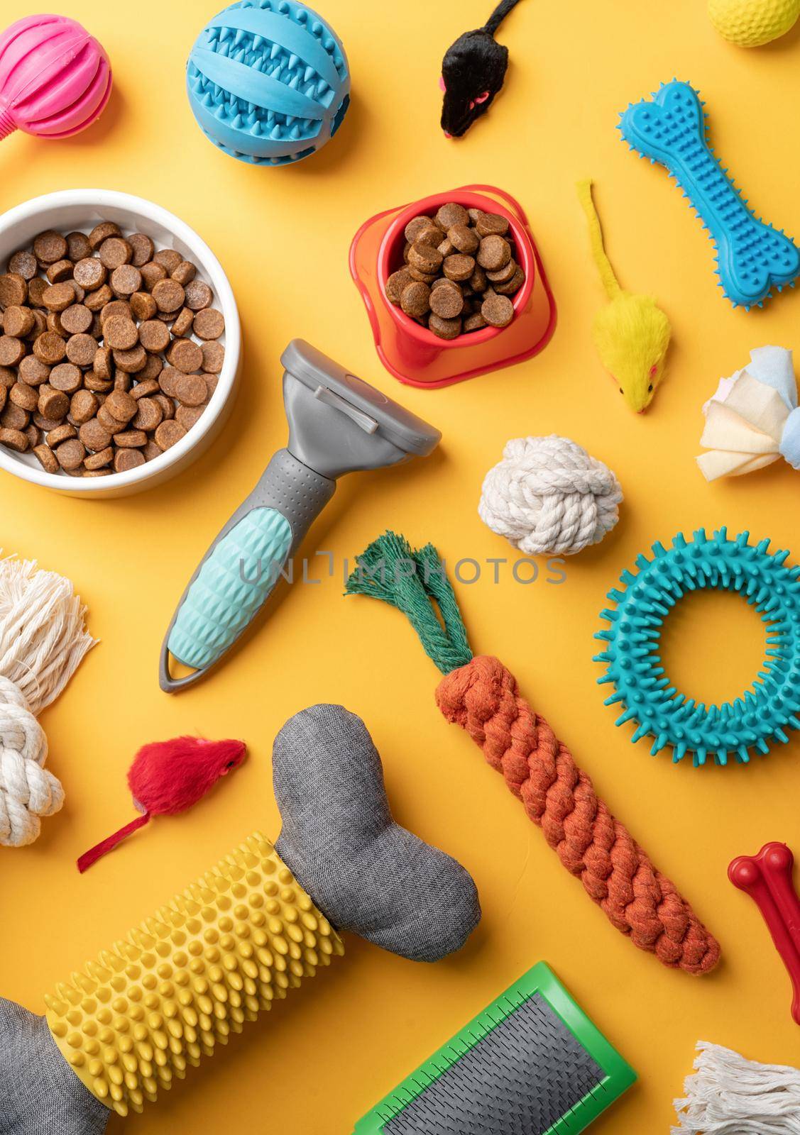 Pet care concept, various pet accessories and tools, toys, balls, brushes on yellow background, flat lay pattern