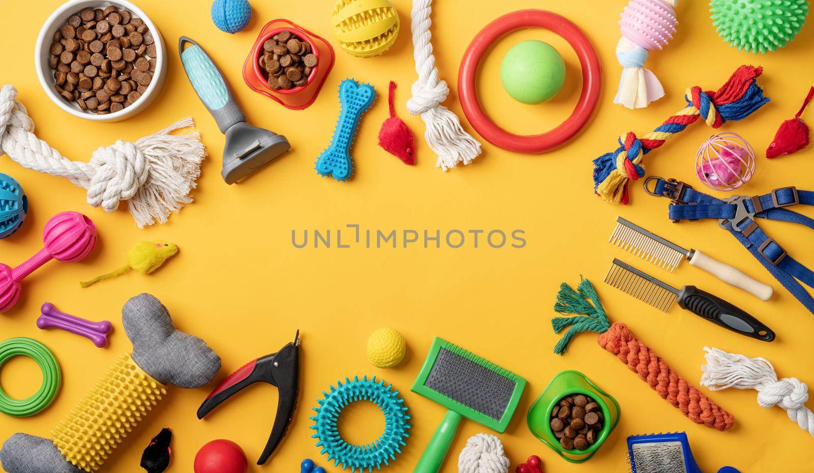 Pet care concept, various pet accessories and tools, toys, balls, brushes on yellow background, flat lay pattern