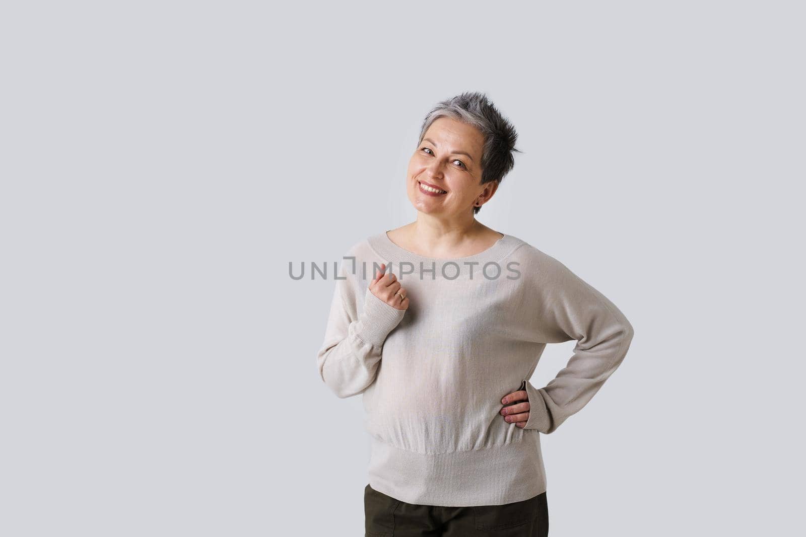 Tender mother look of mature woman with grey hair posing with hand up isolated on white background. Copy space and place for product placement. Toned image. Aged beauty concept.