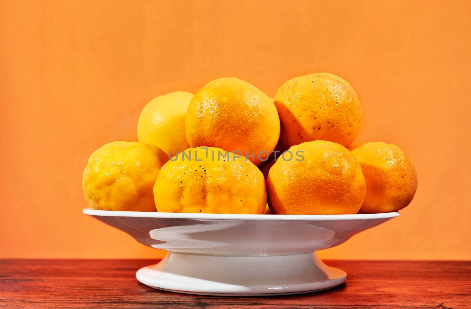 Fresh oranges on white plate on wooden table , healthy eating 