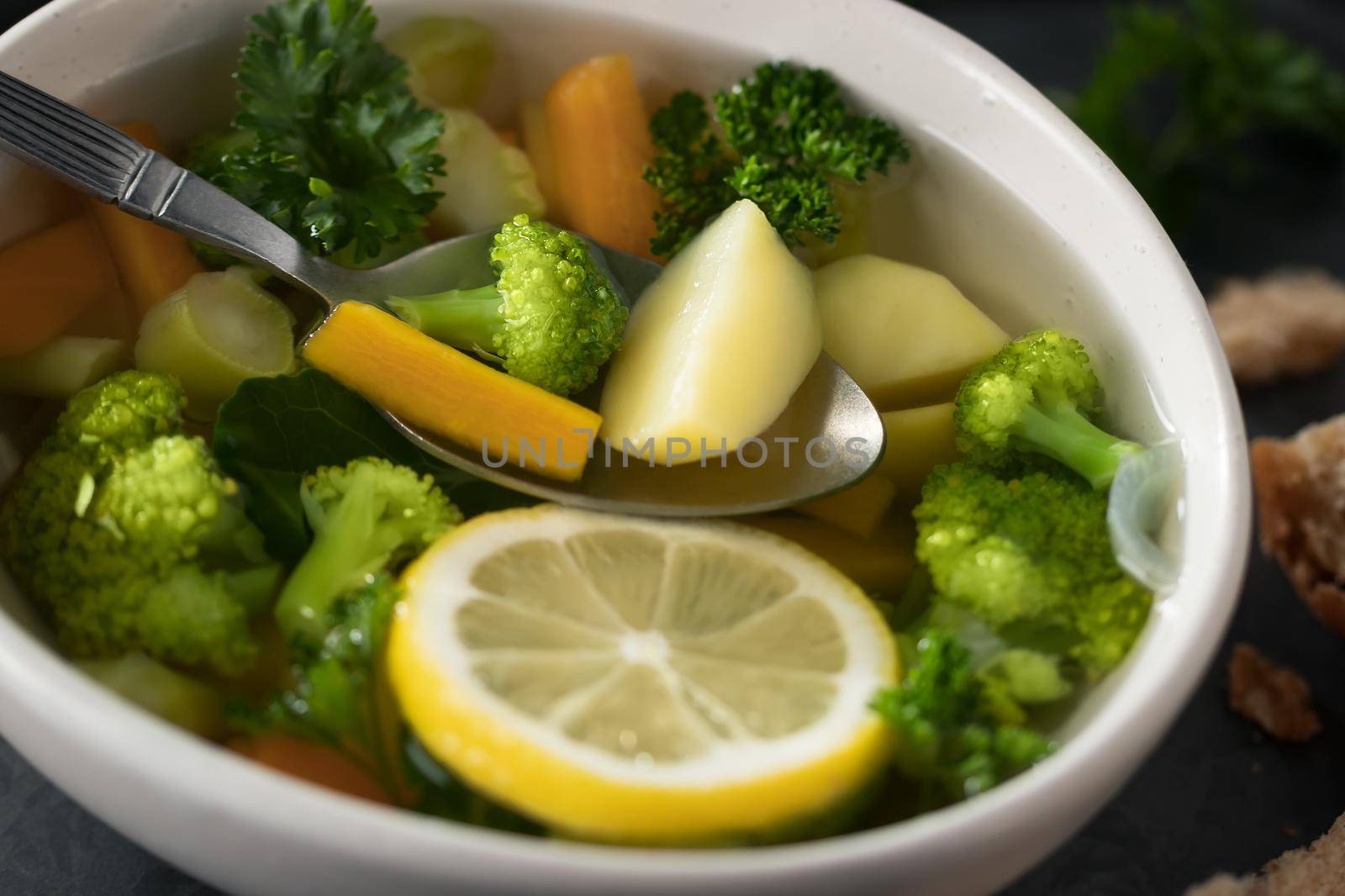 Vegetarian vegetable soup with carrots, broccoli and parsley in a light bowl, close-up.