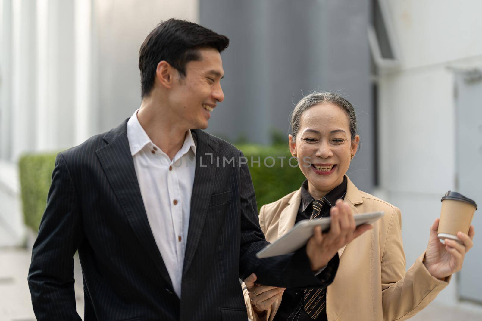 Portrait of young and senior business people working together with digital tablet outdoor