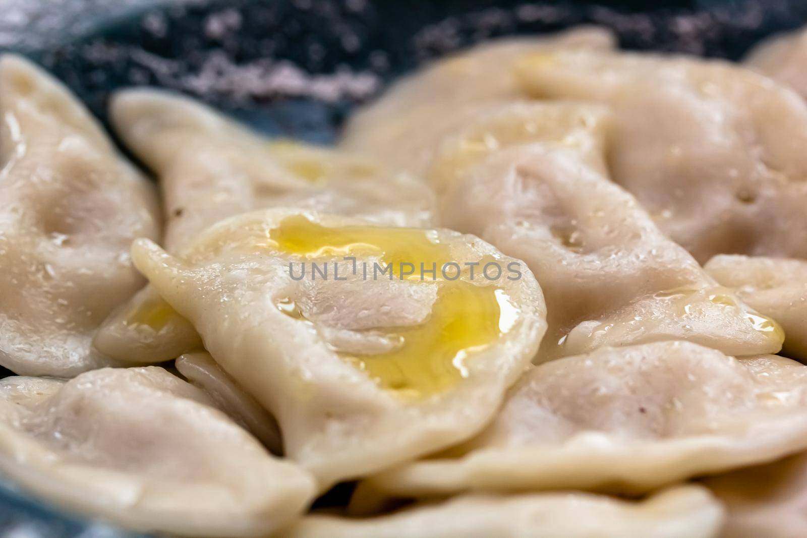 Handmade boiled meat dumplings with bay leaves in large plate on kitchen table