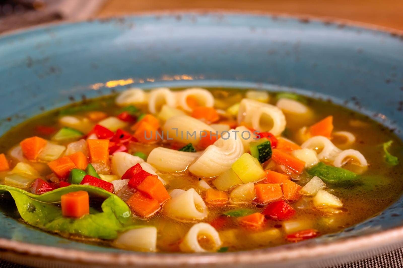 A bowl of minestrone soup with crackers on rustic vintage background.
