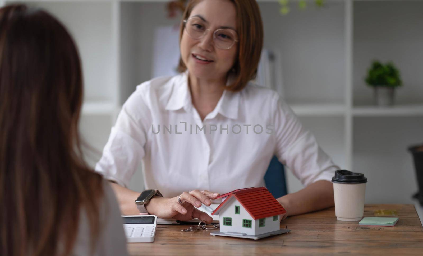 A real estate broker or insurance agent works with home models and home real estate sales contracts within the office, Mortgage loan approval home loan and insurance concept..