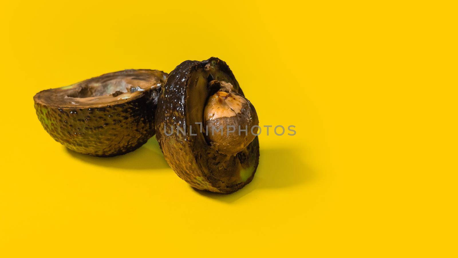 Bad avocado. Ugly fruits on Yellow background. Rotten tropical fruits. Concept of Rotten fruit. Copy Space on Yellow background.