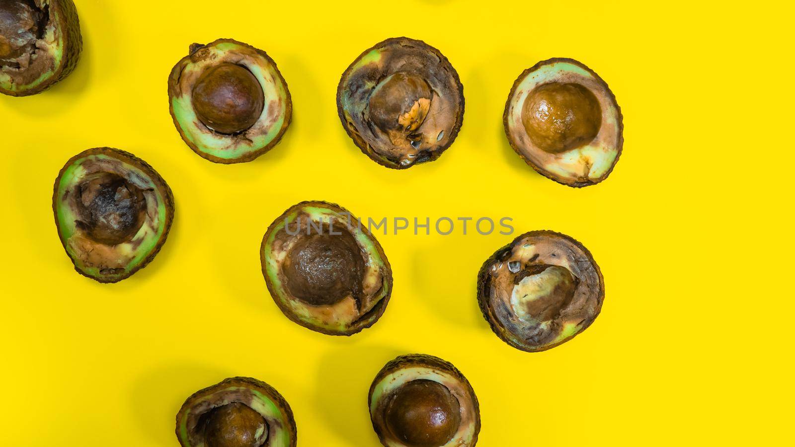 Many Bad Avocado halves on Yellow Background. by RecCameraStock