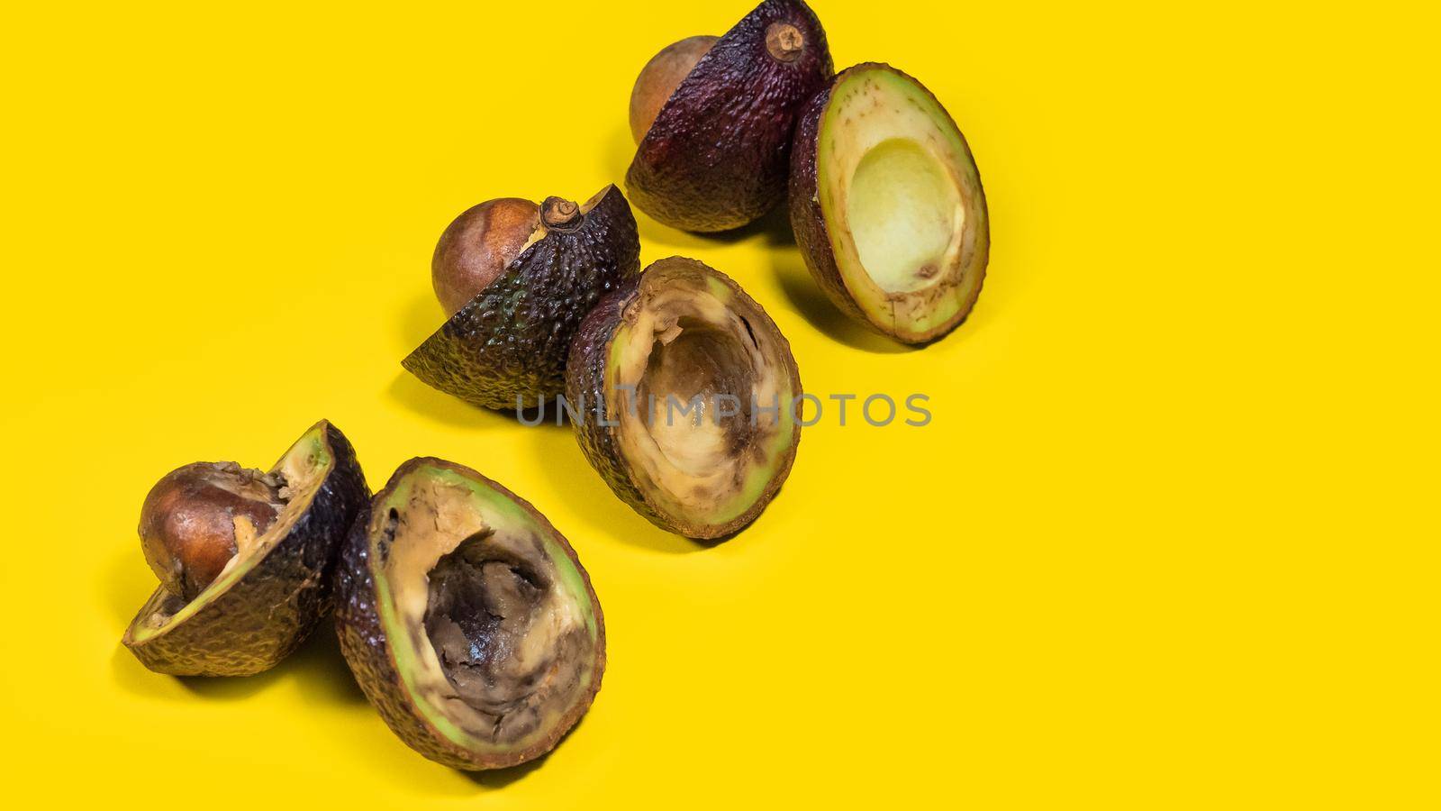 Overripe avocado originally arranged diagonally on a yellow background. Bad Avocado Creative Composition. Unhelthy food Concept. Copy space.