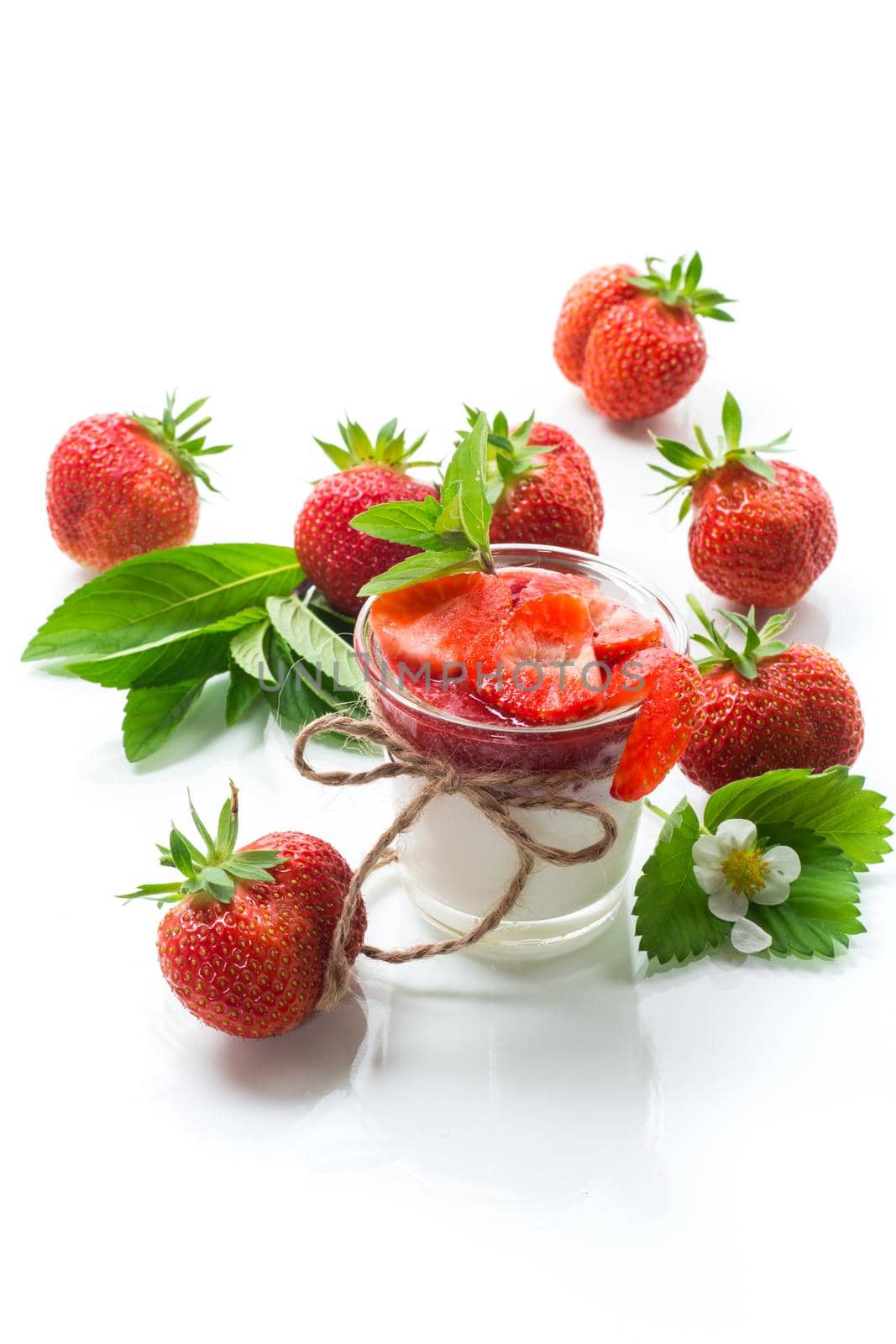 sweet homemade yogurt with strawberry jam and fresh strawberries in a glass, isolated on white background.