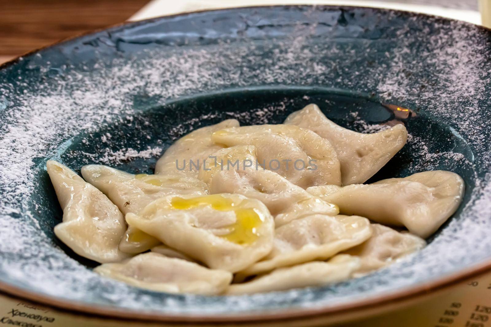 Handmade boiled meat dumplings with bay leaves in large plate on kitchen table