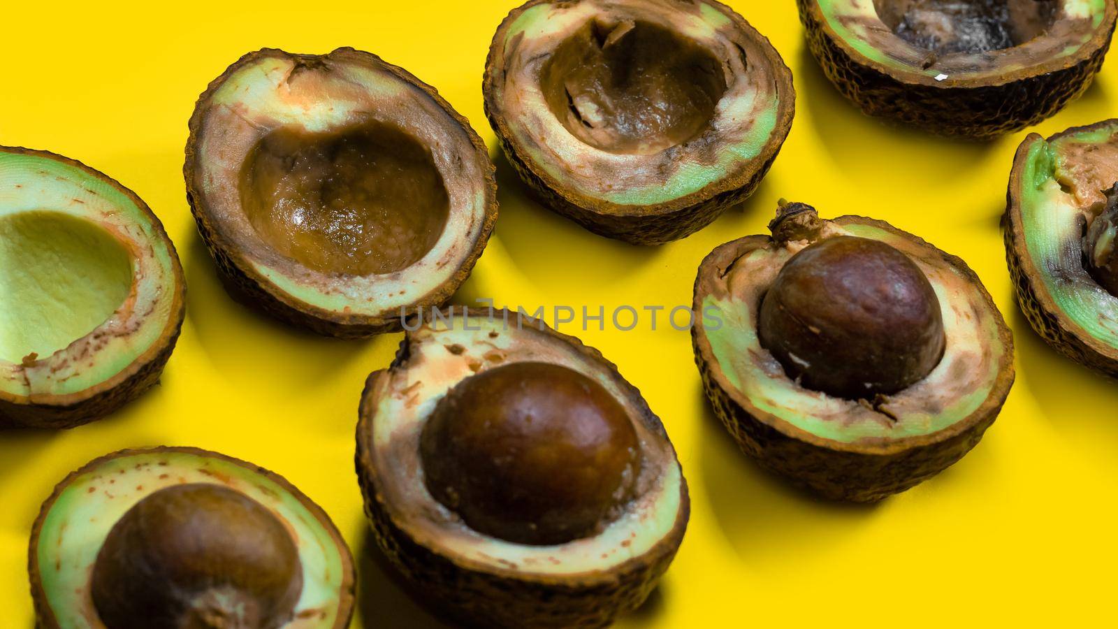 Halfs rotten avocados on yellow table. Unhelthy food Concept. Close up bad avocado on yellow background.