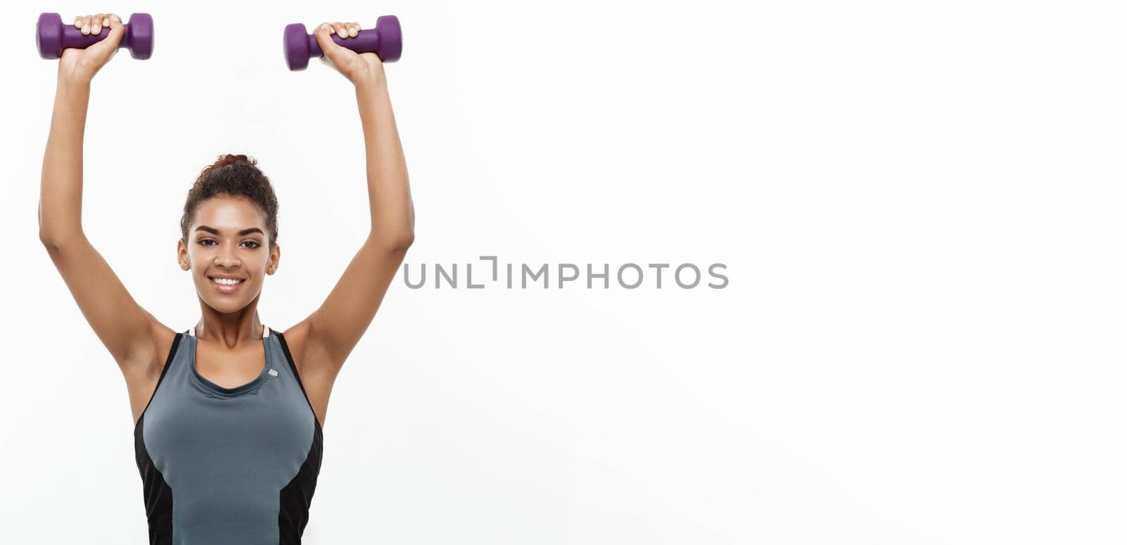 Healthy and Fitness concept - Beautiful American African lady in fitness clothes workout with dumbbell. Isolated on white background. by Benzoix